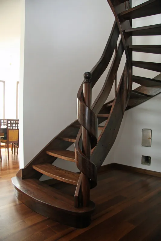 Schody gięte ażurowe w ciemnym drewnie z drewnianą balustradą, zdjęcie 1