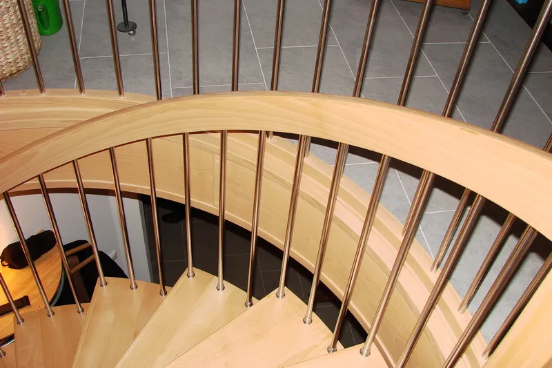 Jasne schody spiralne z metalowymi tralkami i okrągłą galerią, zdjęcie 4